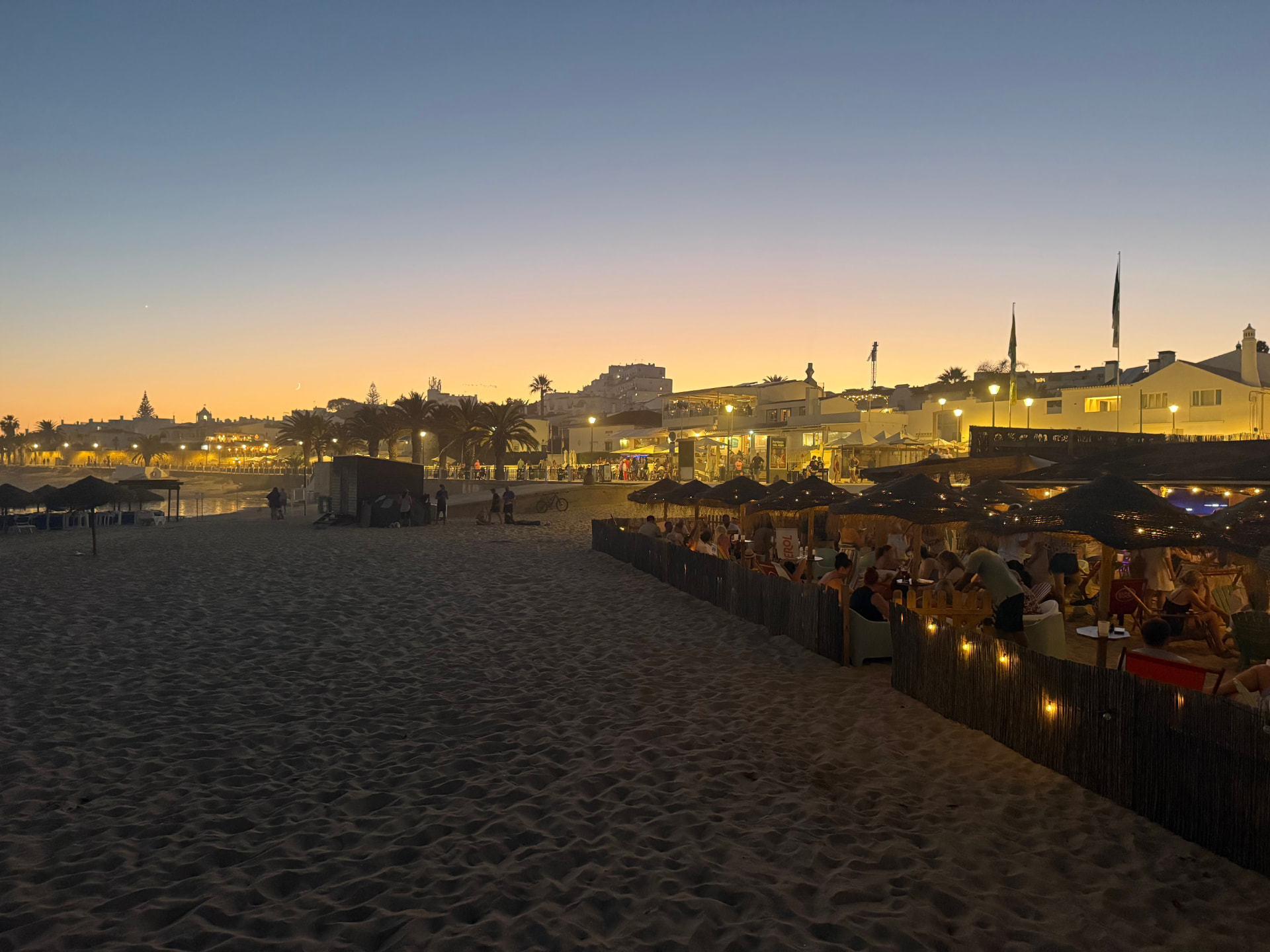 Praia da Luz ao anoitecer com a esplanada iluminada e a vila ao fundo